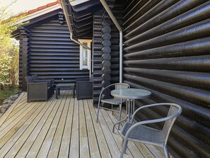A log cabin with a deck, wicker furniture, and a window. - Holiday Home in VÃ¦ggerlÃ¸se (Vaeggerlose)