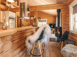 A log cabin interior with a fireplace, wooden walls, a bar area, and a cozy seating arrangement. - Holiday Home in VÃ¦ggerlÃ¸se (Vaeggerlose)
