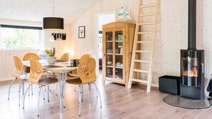A cozy room with a dining table, chairs, a cabinet, a ladder, and a fireplace. - 6 Person Holiday Home in Henne (Henne)