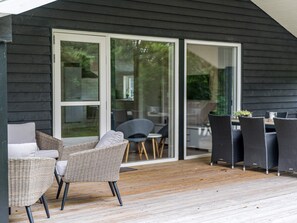 A covered outdoor area with wicker furniture and a wooden deck.