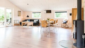 A spacious living area with a high ceiling, wooden flooring, a sofa, dining table, chairs, and a fireplace. - 6 Person Holiday Home in Henne (Henne)