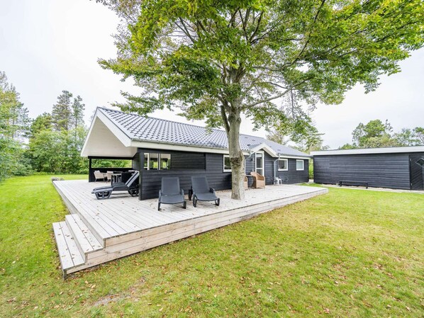 A modern house with a deck, a covered outdoor seating area, and a garage.