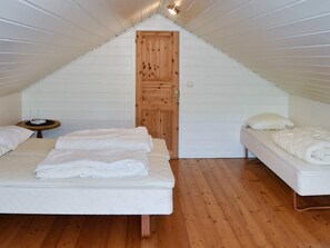 Ett litet, triangulärt vindsrum med två sängar, en trädörr och ett litet bord.