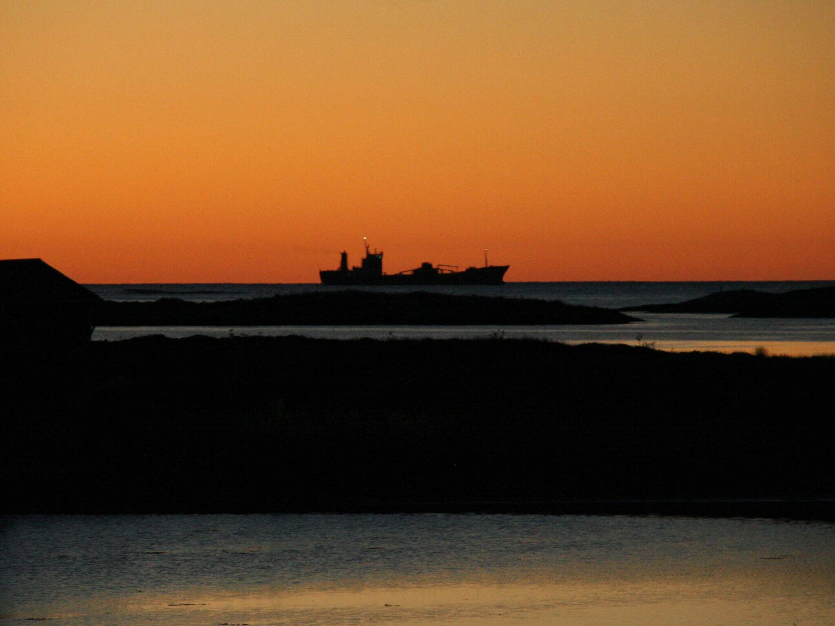 A ship silhouette against a sunset sky.