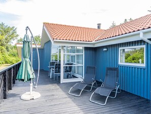 Een overdekt buitengebied met een tafel, stoelen, een groene parasol en een terras.