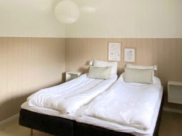 A bedroom with a double bed, two bedside tables, and a wall-mounted light fixture.