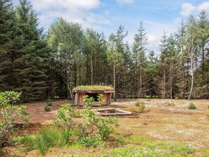 Een rustieke hut met rieten dak, omgeven door dicht bos.