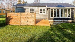 A two-story house with a fenced backyard, a covered patio, and a satellite dish. - 6 Person Holiday Home in Vaeggerlose (Vaeggerlose)