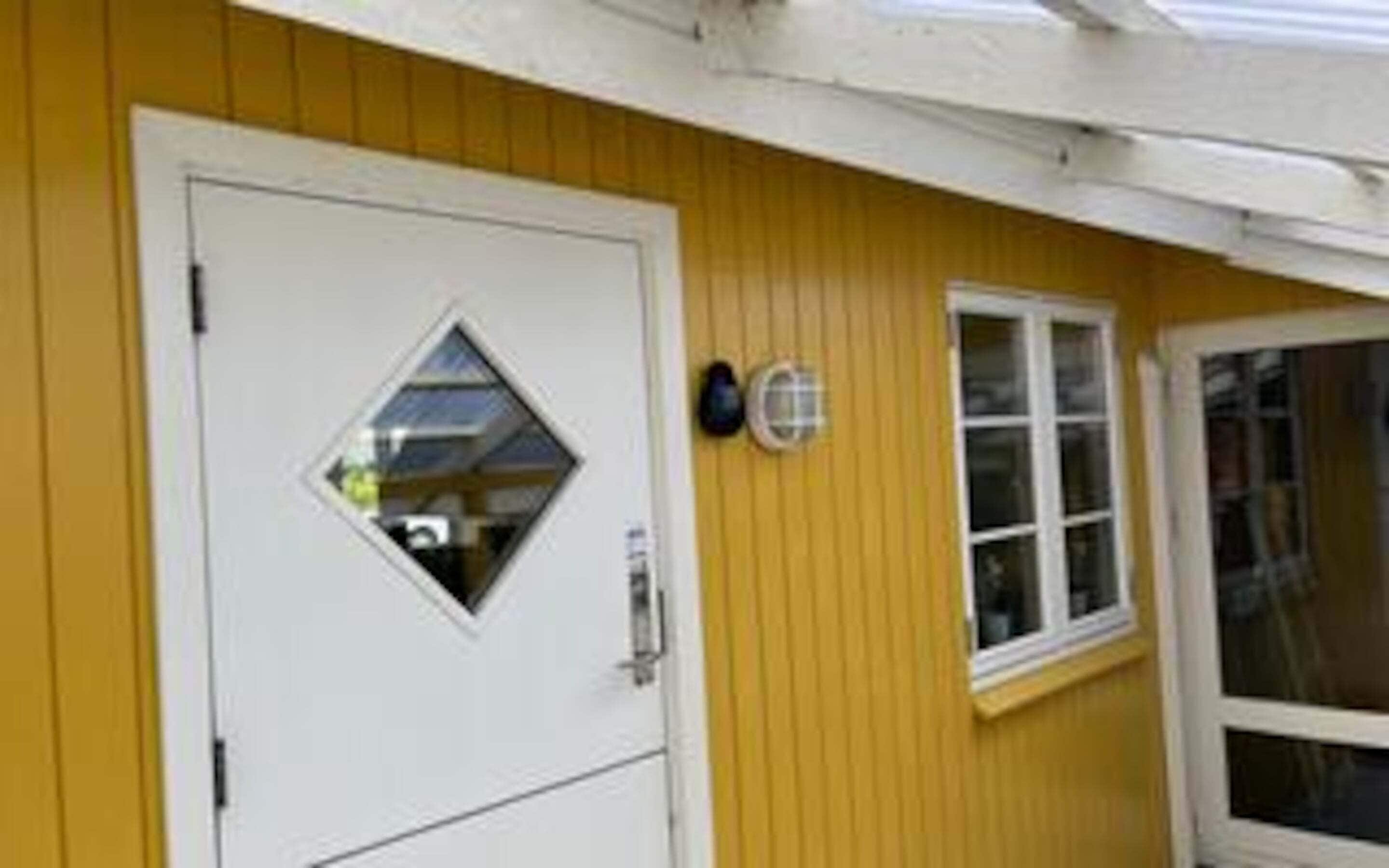 A yellow building with a white door and a window.