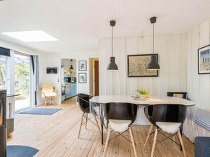 A modern kitchen with a dining area, wooden floors, and pendant lighting. - 2 Person Holiday Home in Henne (Henne)