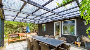 A covered patio with a table and chairs, a wooden bench, and a potted plant. - 2 Person Holiday Home in Henne (Henne)