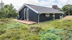 A modern, single-story building with a dark exterior, a sloped roof, and a wooden deck. - 6 Person Holiday Home in Fano (Fano)