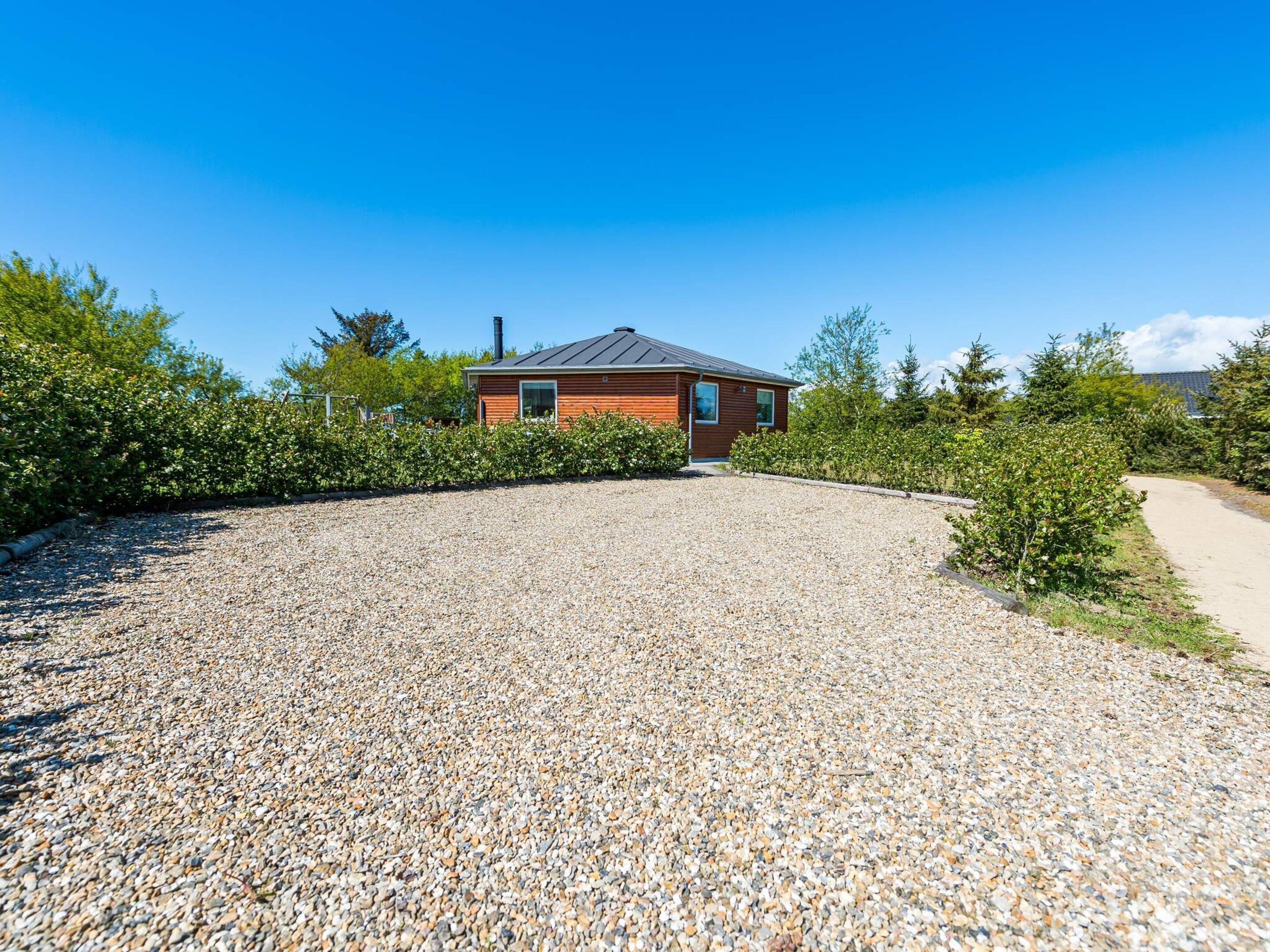 A modern house with a gravel driveway and a wooden exterior.