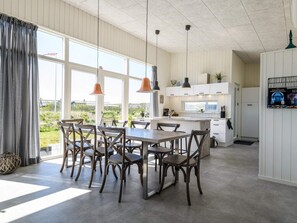 A modern kitchen with white cabinets, a central island, pendant lighting, and a view of the outdoors.