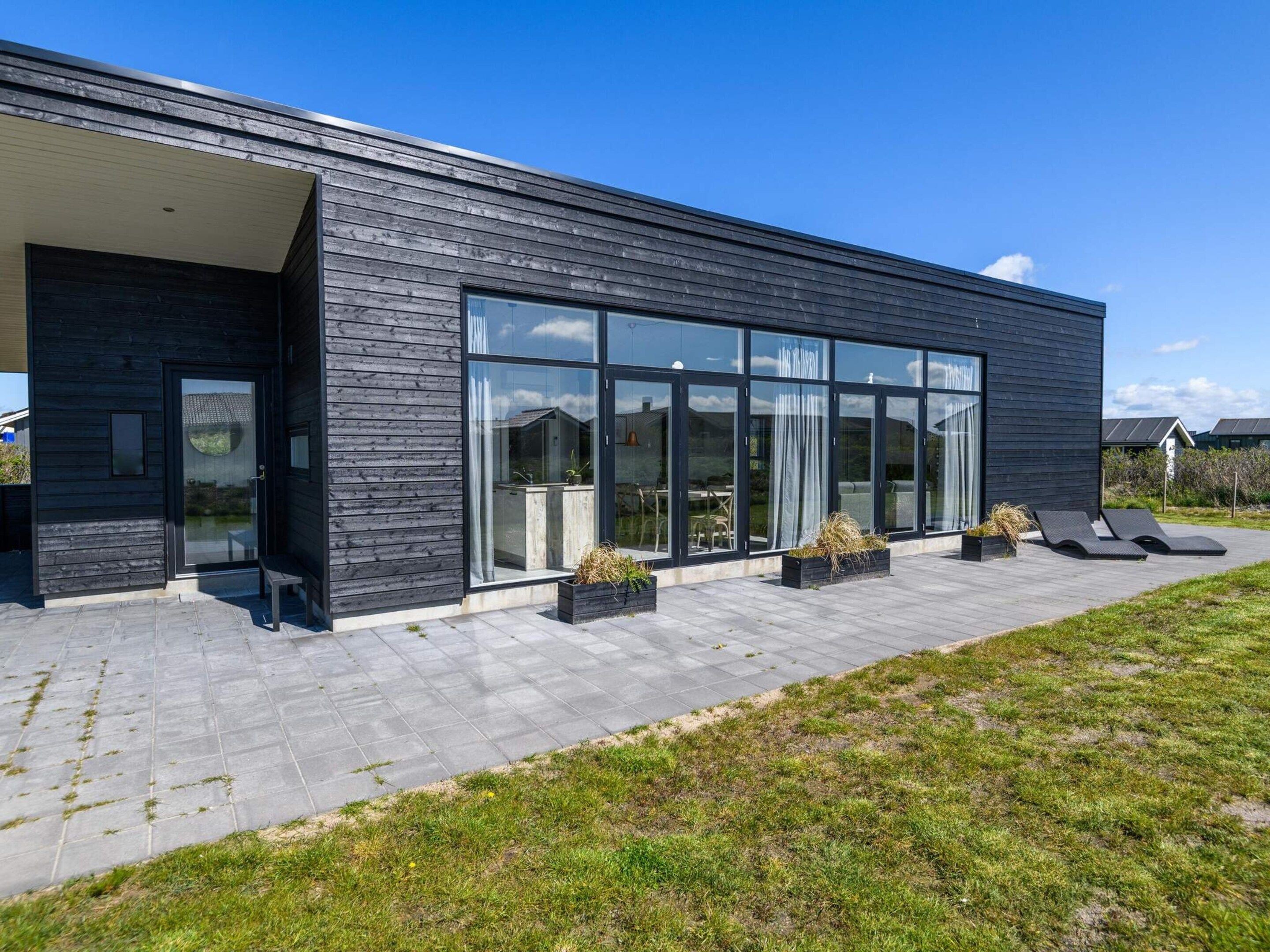 A modern building with large glass windows, a flat roof, and a paved walkway.
