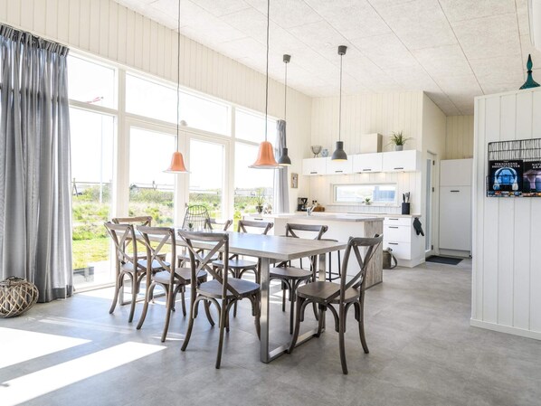 A spacious kitchen with white cabinets, a central island, and pendant lighting.