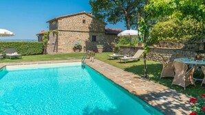 A stone building with a pool, outdoor seating, and a view of the landscape. - Holiday Home in Cortona (Cortona)