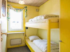 A bunk bed room with yellow walls, a window with curtains, a radiator, and a door. - 6 Person Holiday Home in Henne (Henne)