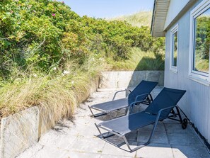 A patio with two lounge chairs and a concrete wall. - 6 Person Holiday Home in Henne (Henne)