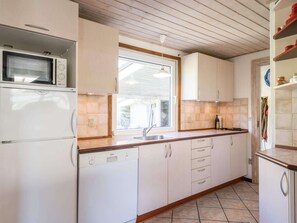 Compact kitchen with microwave and Bosch dishwasher, featuring a window and clean, organized design.
