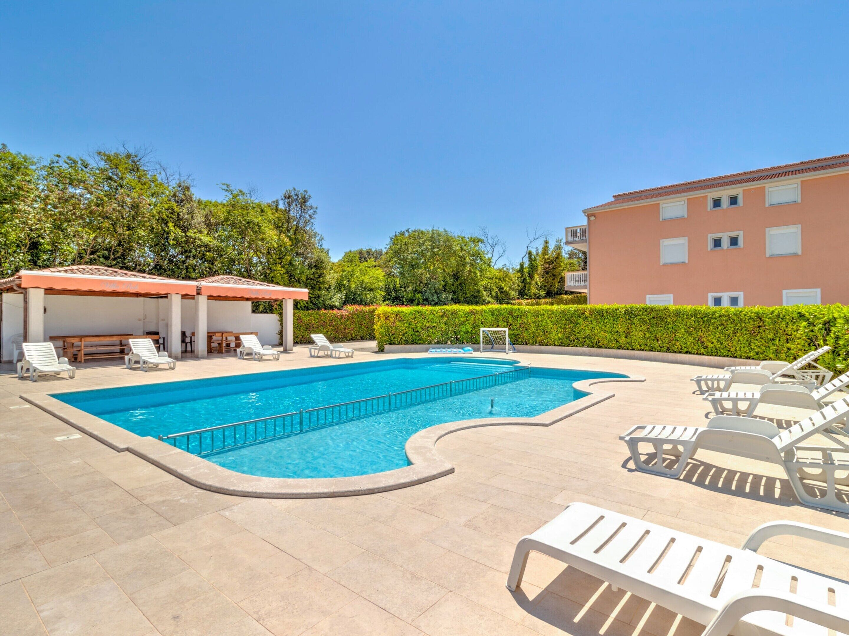 A swimming pool with lounge chairs and a covered seating area.