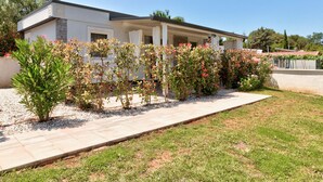Une maison moderne dotée d’un porche abrité, entourée de jardins bien entretenus et d’un chemin de gravier.