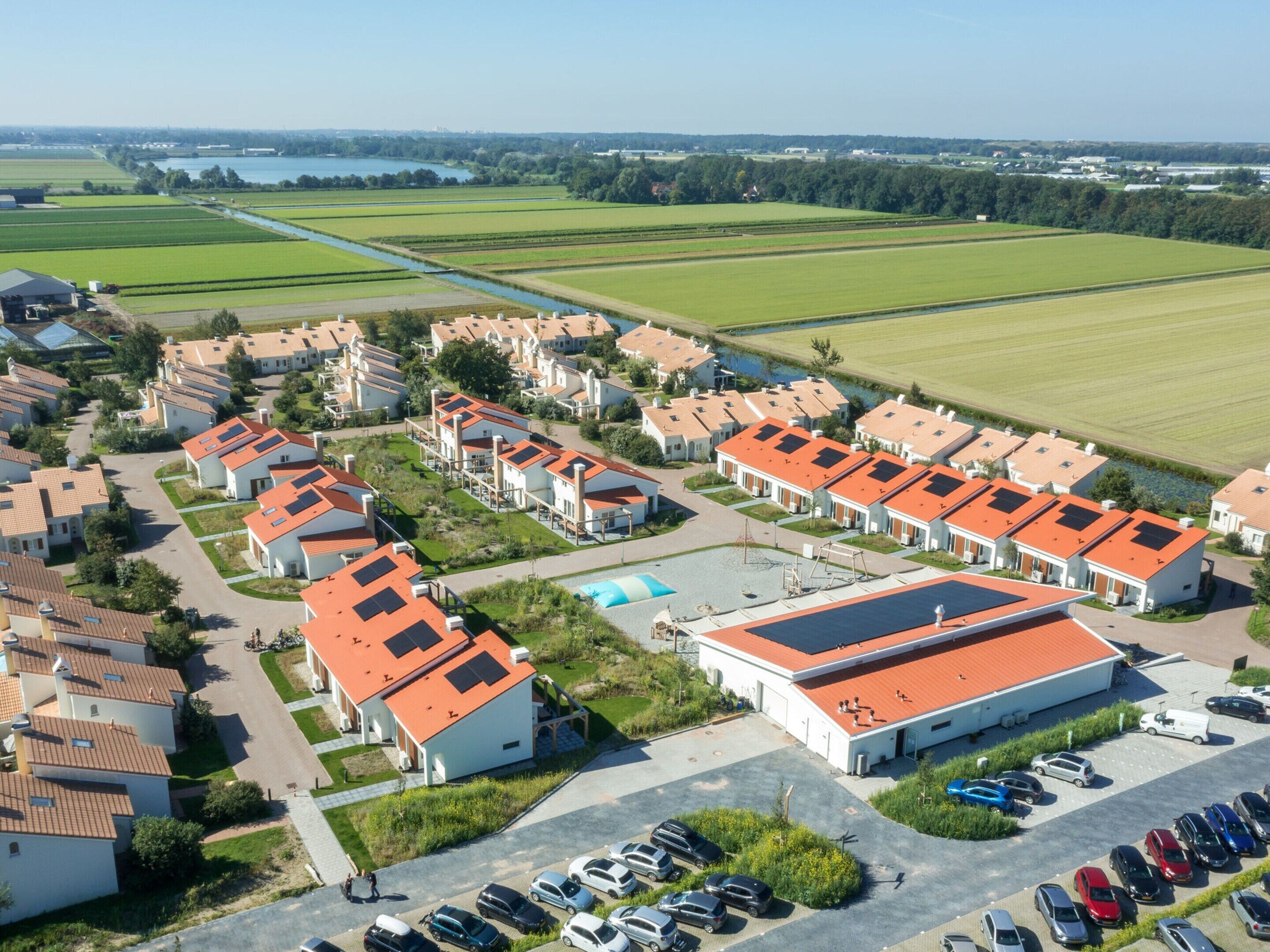 Una zona residenziale con case moderne, una piscina e un edificio grande con tetto rosso.