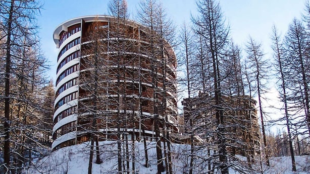A multi-story building with a circular design, surrounded by snow-covered trees and a clear sky. - Apartment in Cervinia With Ski Access (Valtournenche)