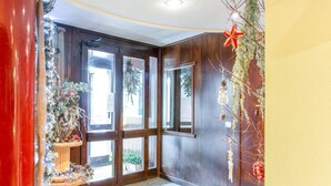 A room with wooden walls, a large window, and a Christmas tree. - Apartment in Cervinia With Ski Access (Valtournenche)
