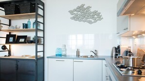Une cuisine moderne avec des meubles blancs, un évier en acier inoxydable et une machine à café.