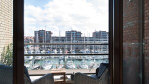 A balcony with wicker furniture overlooking a marina with boats and buildings in the background. - Appealing Apartment in Den Haag With Balcony (The Hague)