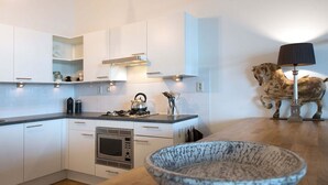 A modern kitchen with white cabinetry, a gas stove, a microwave, and a wooden countertop. - Appealing Apartment in Den Haag With Balcony (The Hague)