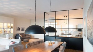 A modern living room with a wooden dining table, grey sofas, and black pendant lights. - Appealing Apartment in Den Haag With Balcony (The Hague)