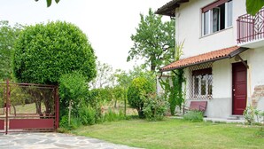 A stone pathway leading to a white building with a red door and a balcony. - Rustic Moncucco Village Retreat (Moncucco Torinese)