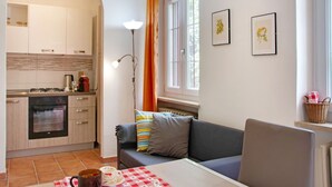 A modern kitchen with a built-in oven and a dining area with a checkered tablecloth. - Rustic Moncucco Village Retreat (Moncucco Torinese)