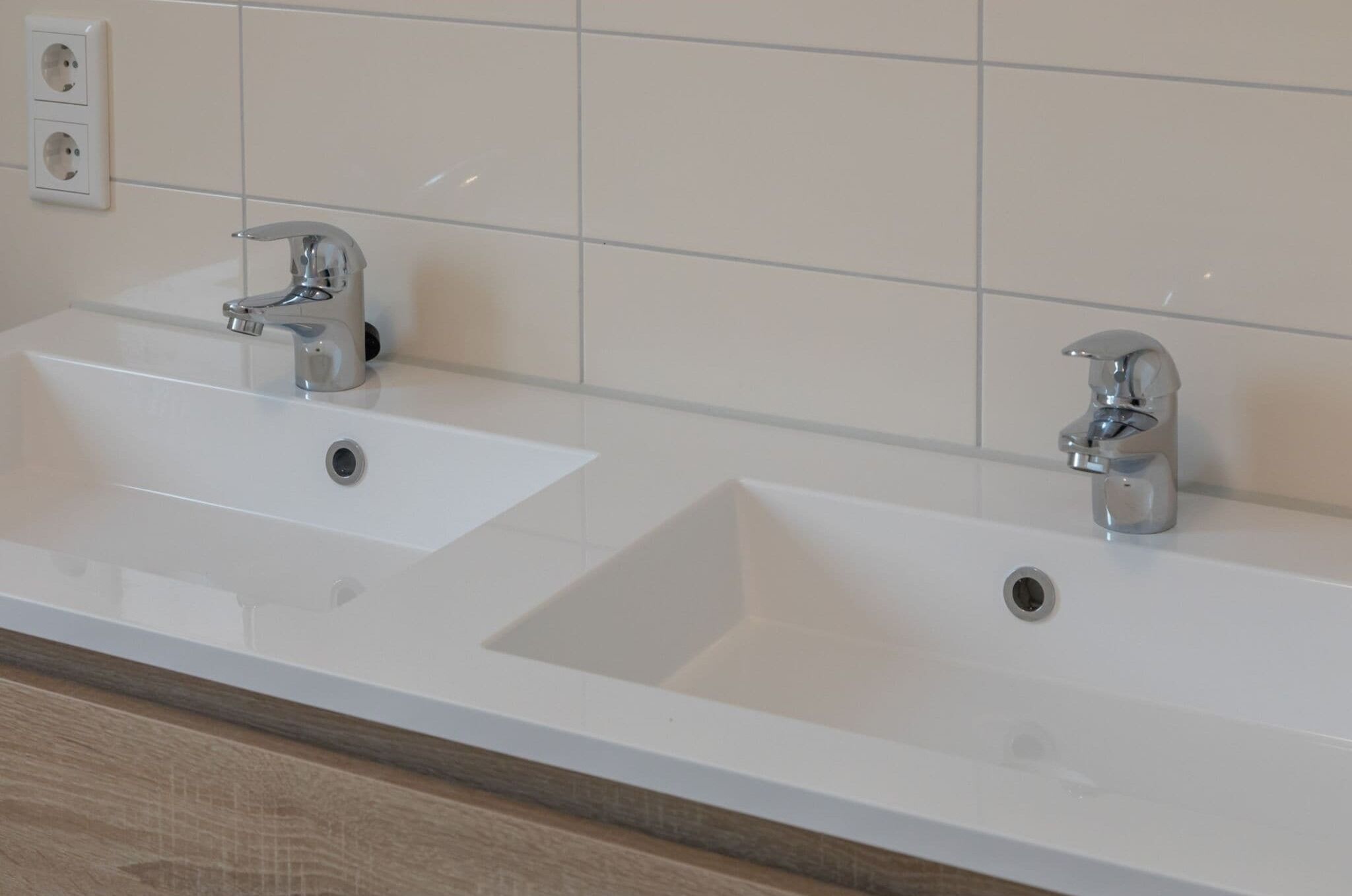 Een badkamer met twee wasbakken, een spiegel en een houten aanrechtblad.