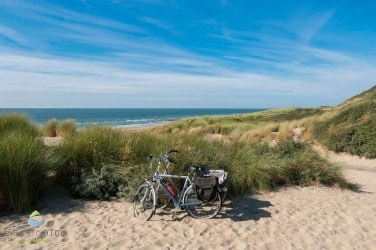 Une plage de sable avec des dunes, un vĂ©lo et une vue dĂ©gagĂ©e sur lâocĂ©an.