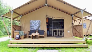 A tent with a wooden deck, two chairs, a table, and a kitchen area with a sink and cabinets. - Homely Tent with Kitchen & Shower near Beach & Campsite ('s-Gravenzande)