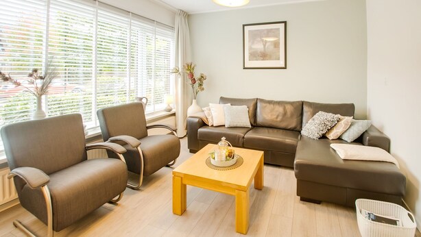 A living room with a brown leather sofa, a brown armchair, a wooden coffee table, and a white basket. - Holiday Home in Kilder Near Bergherbos (Kilder)