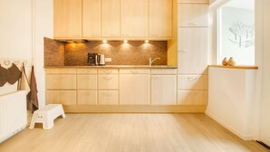 A modern kitchen with wooden cabinets, a countertop, and a window with a view. - Holiday Home in Kilder Near Bergherbos (Kilder)