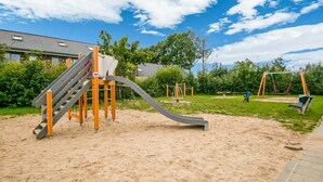 A playground with a slide, climbing structure, and swings. - Holiday Home in Kilder Near Bergherbos (Kilder)