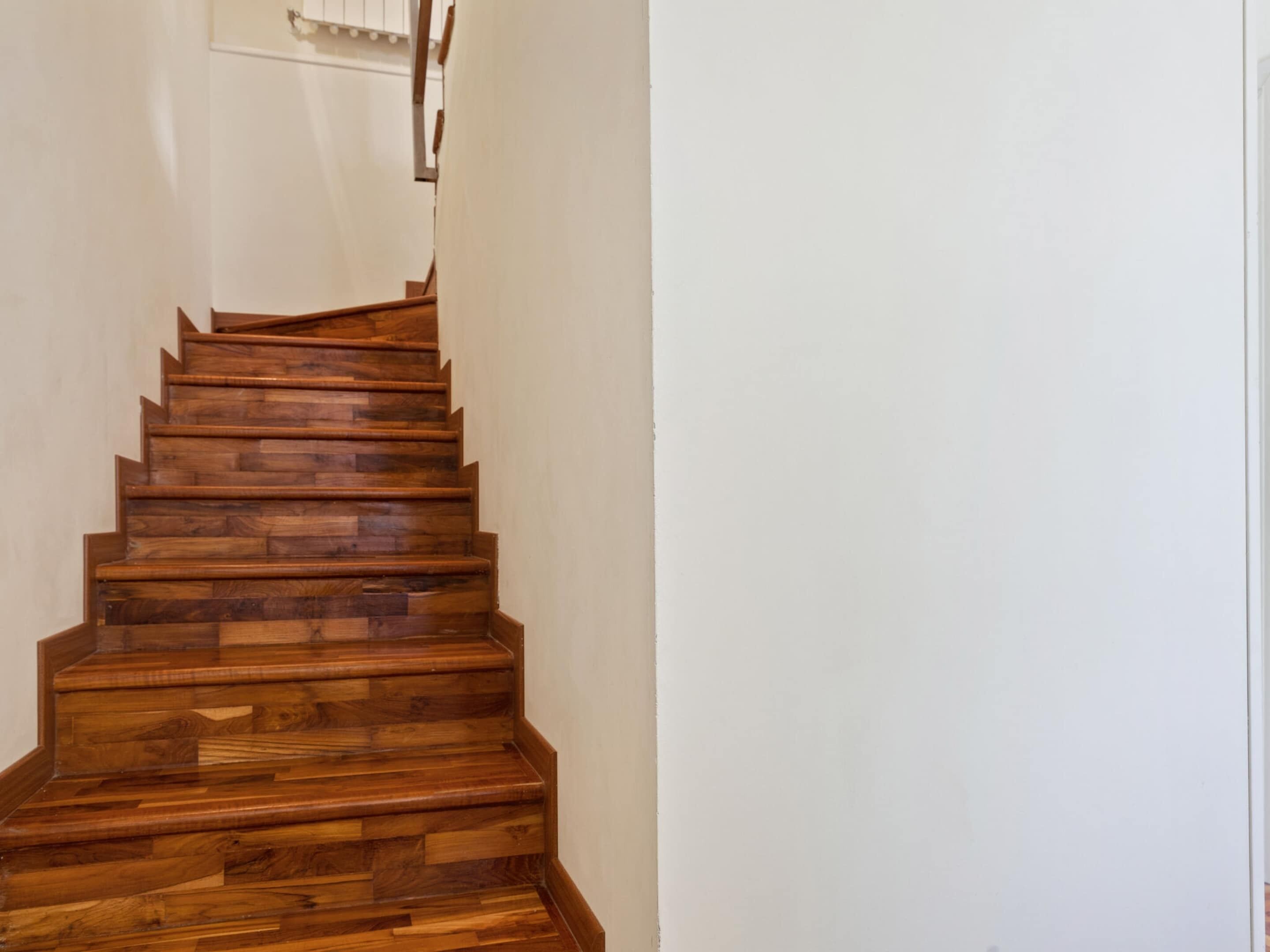 Eine Holztreppe mit Handlauf, die zu einer Tür führt.