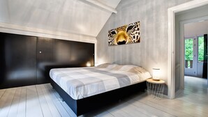 Une chambre à coucher moderne avec un grand lit, une tête de lit, une œuvre d’art accrochée au mur et une table de chevet avec une lampe.