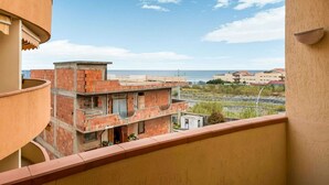A balcony with a view of a coastal area, featuring a brick building and a clear sky.