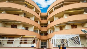 A multi-story building with a central staircase, balconies, and a gated entrance.