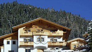 A multi-story wooden chalet with balconies, set against a snowy forest backdrop. - Delightful Apartment in Zell am Ziller With a View (Gerlosberg)
