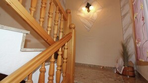 A wooden staircase with a wall-mounted light fixture and a potted plant. - Delightful Apartment in Zell am Ziller With a View (Gerlosberg)
