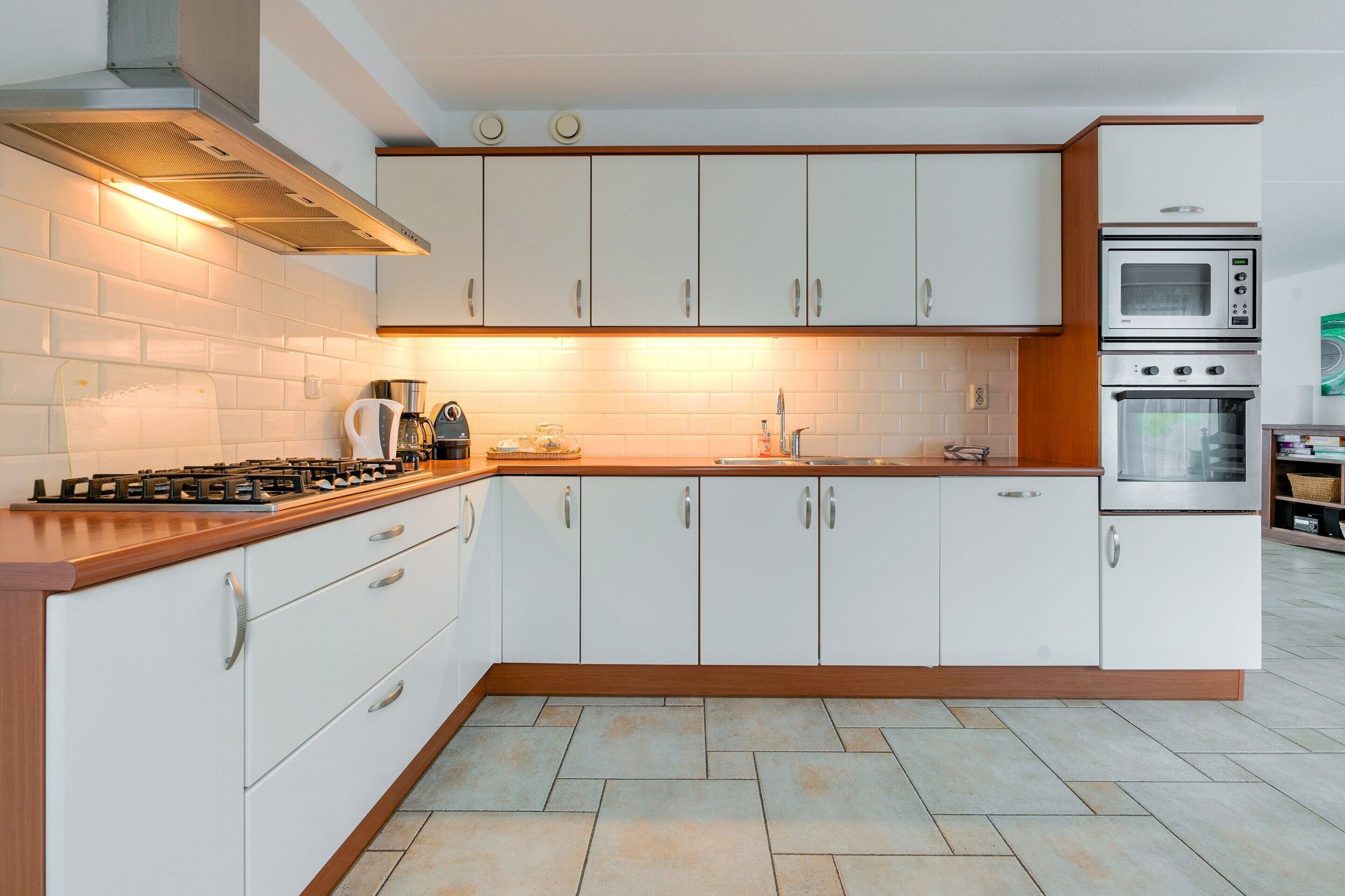 Een moderne keuken met witte kasten, een gasfornuis, een oven en een magnetron.