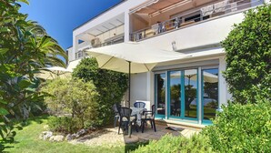 A modern two-story house with a patio area featuring outdoor furniture and a large umbrella. - Scenic Apartment With Garden in Medulin (Medulin)