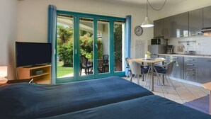 A bedroom with a large bed, a TV, and a sliding glass door leading to a balcony with a view of greenery. - Scenic Apartment With Garden in Medulin (Medulin)